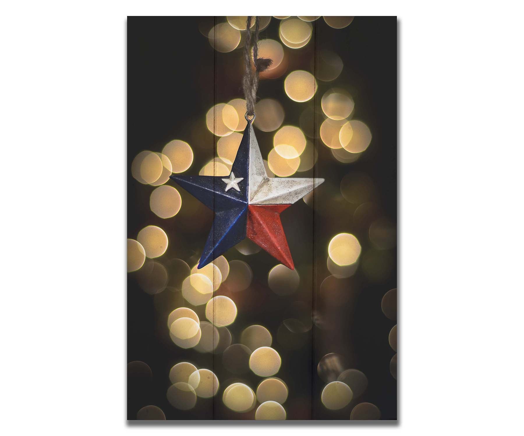 A photo of a christmas ornament of a star painted like the Texas state flag, with yellow bokeh in the background. Printed on a box board.