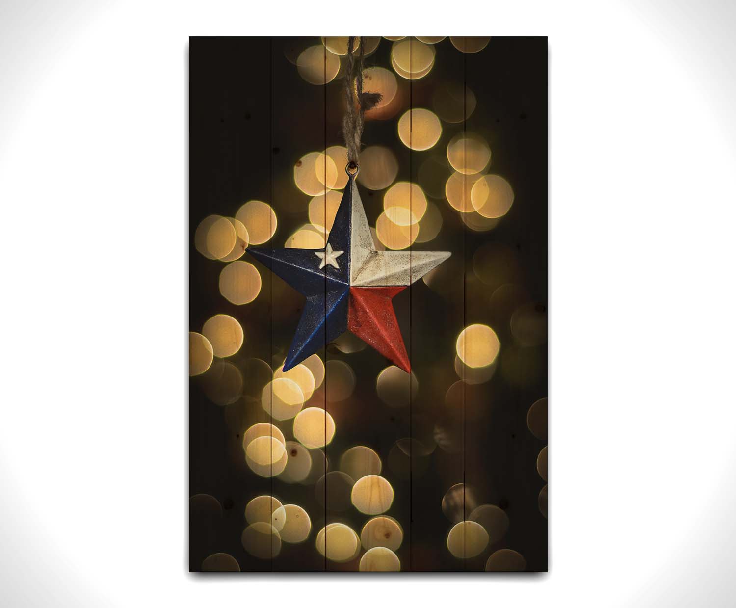 A photo of a christmas ornament of a star painted like the Texas state flag, with yellow bokeh in the background. Printed on a wood pallet.