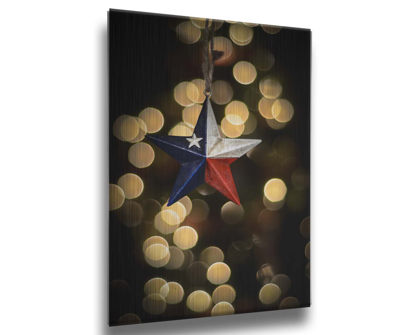 A photo of a christmas ornament of a star painted like the Texas state flag, with yellow bokeh in the background. Printed on metal.