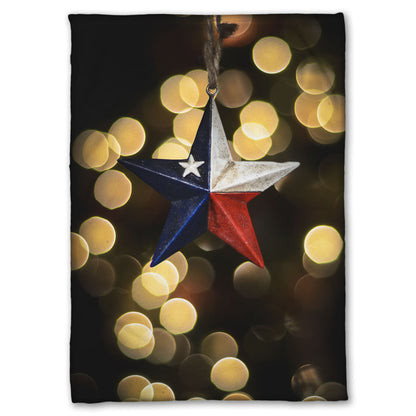 A coral fleece blanket printed with the image of a star-shaped texas flag christmas ornament.