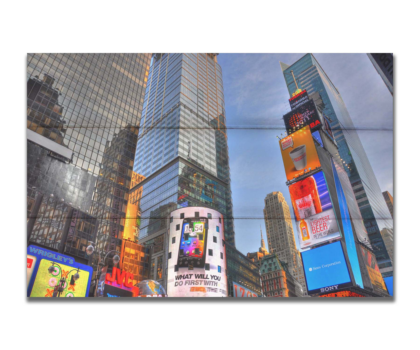 A photo looking up at the buildings and advertisements of Times Square in New York. Printed on a box board.