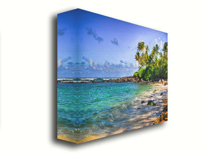 A photo of Laniākea beach. The water is a vibrant blue-green, and the stony beach circles around in the background where lush foliage and palm trees grow under a bright blue sky. Printed on canvas.