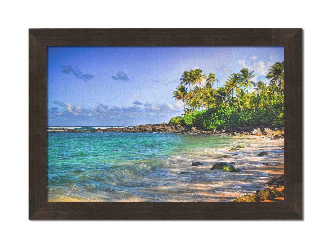 A photo of Laniākea beach. The water is a vibrant blue-green, and the stony beach circles around in the background where lush foliage and palm trees grow under a bright blue sky. Printed on canvas and framed.