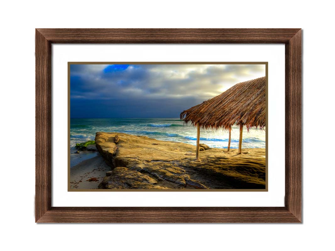 A photo of the palapa at Windansea beach, sitting on a rock in  the fading sunshine. Printed on paper, matted, and framed.