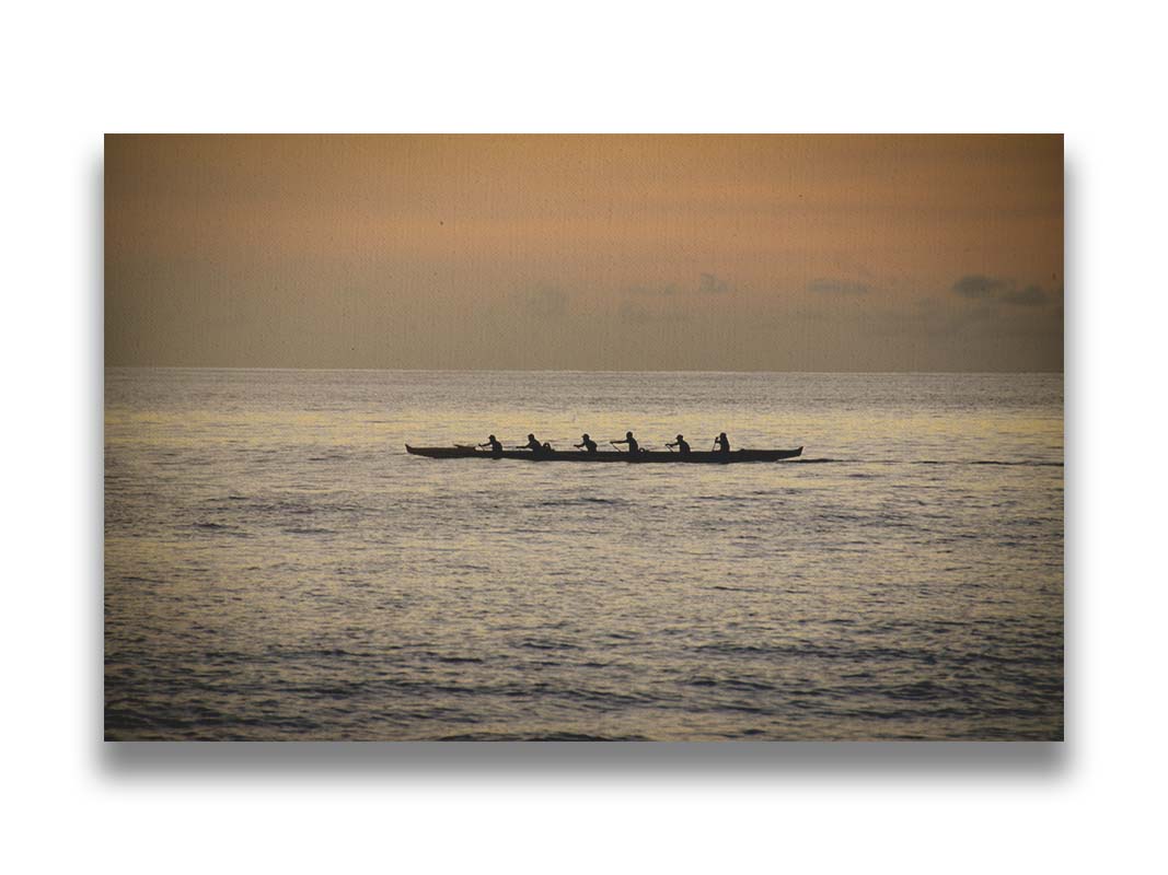 A photo of an outrigger canoe at sea, silhouetted against an orange sky. Printed on canvas.