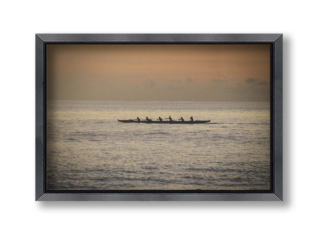 A photo of an outrigger canoe at sea, silhouetted against an orange sky. Printed on canvas and framed.