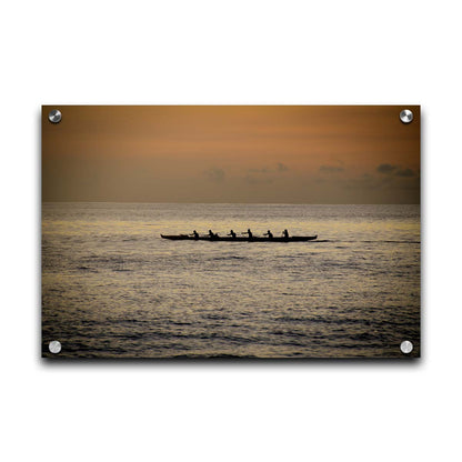 A photo of an outrigger canoe at sea, silhouetted against an orange sky. Printed on acrylic.