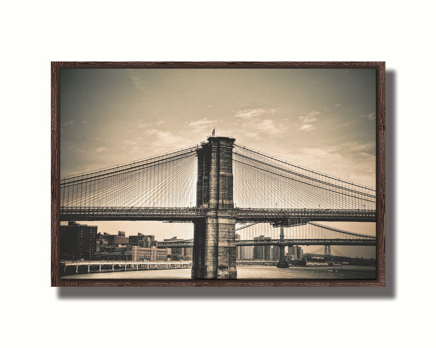 A sepia photo of the brooklyn bridge from the side, accented with a dark vignette. Printed on canvas in a float frame.