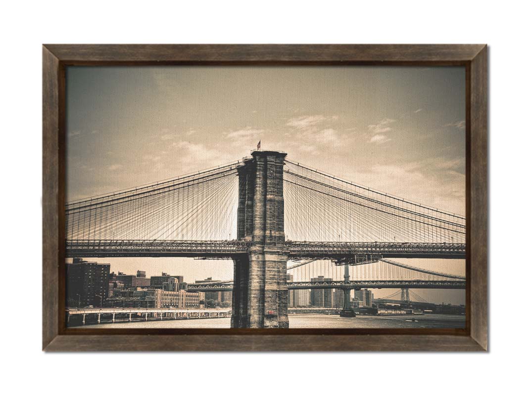 A sepia photo of the brooklyn bridge from the side, accented with a dark vignette. Printed on canvas and framed.