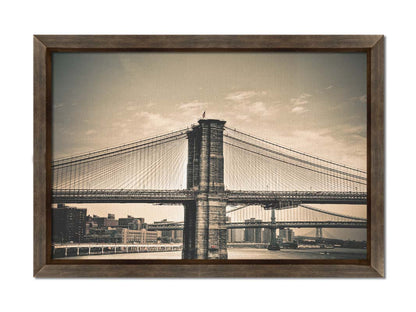 A sepia photo of the brooklyn bridge from the side, accented with a dark vignette. Printed on canvas and framed.