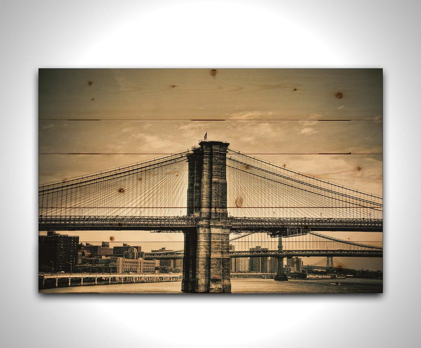 A sepia photo of the brooklyn bridge from the side, accented with a dark vignette. Printed on a wood pallet.