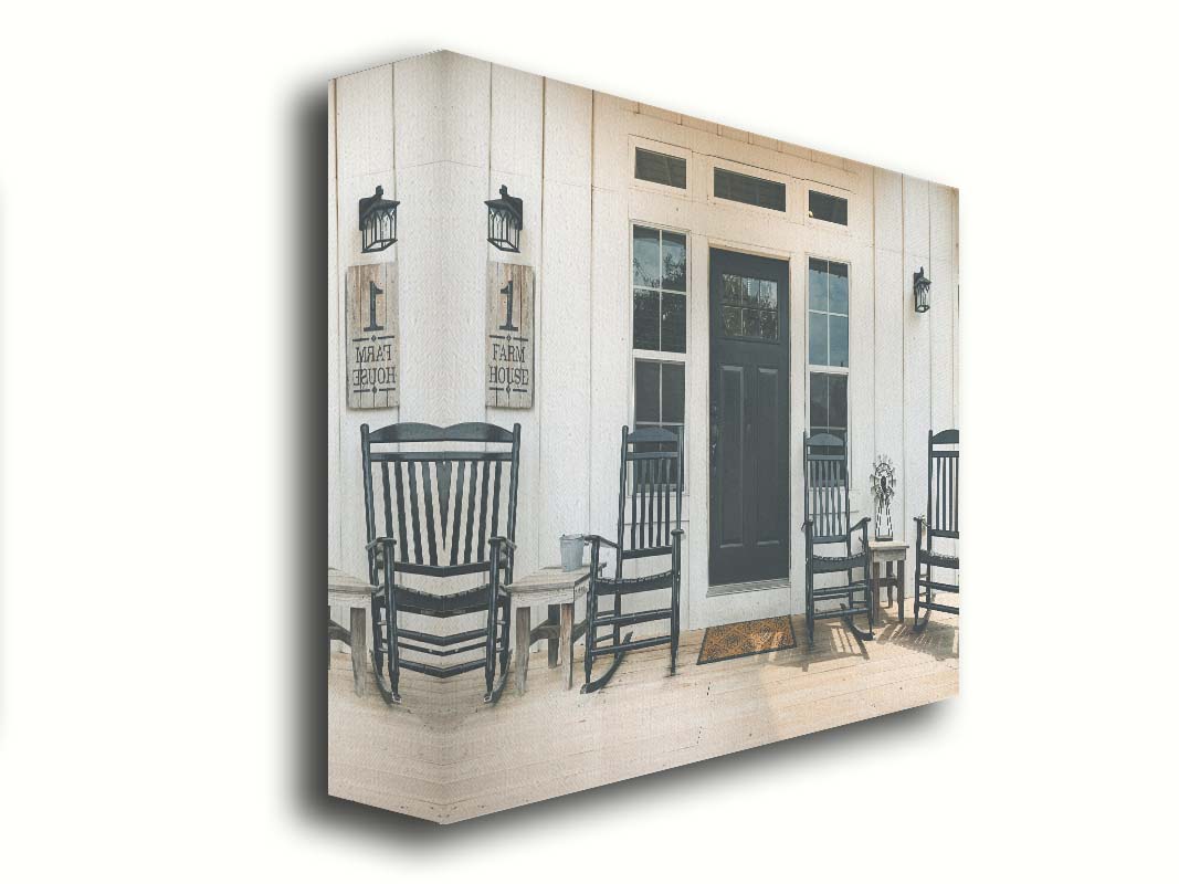 A photo of the door and front porch of a white house, with four black rocking chairs and a black door. Printed on canvas.