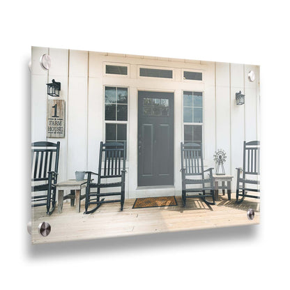 A photo of the door and front porch of a white house, with four black rocking chairs and a black door. Printed on acrylic.