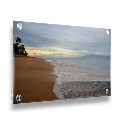 A photo of a cloudy sunrise on the Kaʻanapali shore, looking out to sea. Sailboats can be seen out on the water. Printed on acrylic.