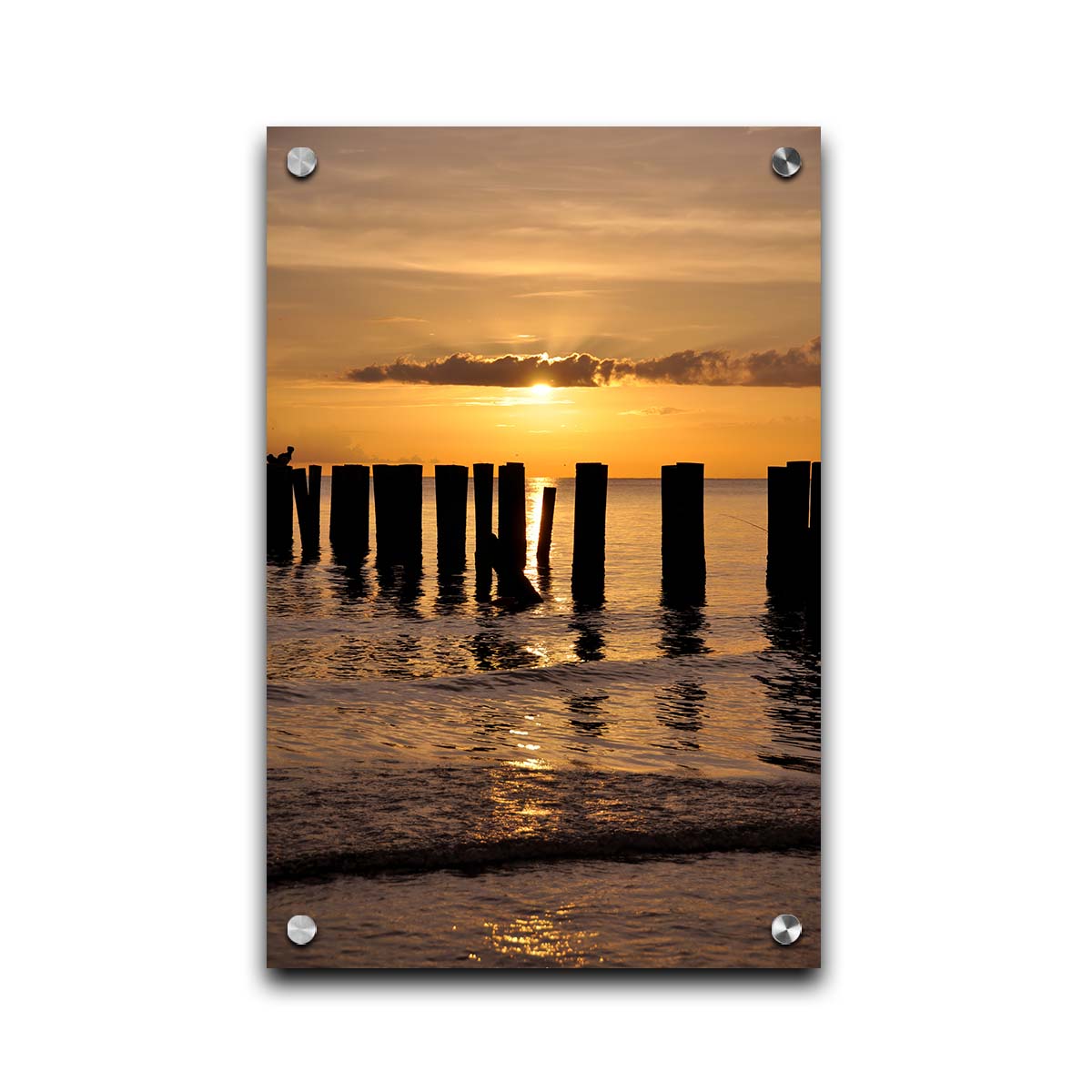 A photo of the remains of the Naples Beach pier in Florida. The sun is low on the horison and silhouettes the pillars in the sea. Printed on acrylic.