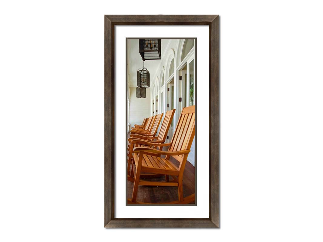 A photo looking down a row of rocking chairs on a porch in O'ahu, Hawaiʻi. Printed on paper, matted, and framed.