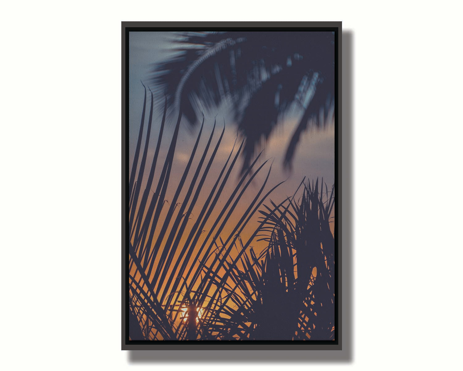 A photo of silhouetted palms at sunset. Printed on canvas in a float frame.