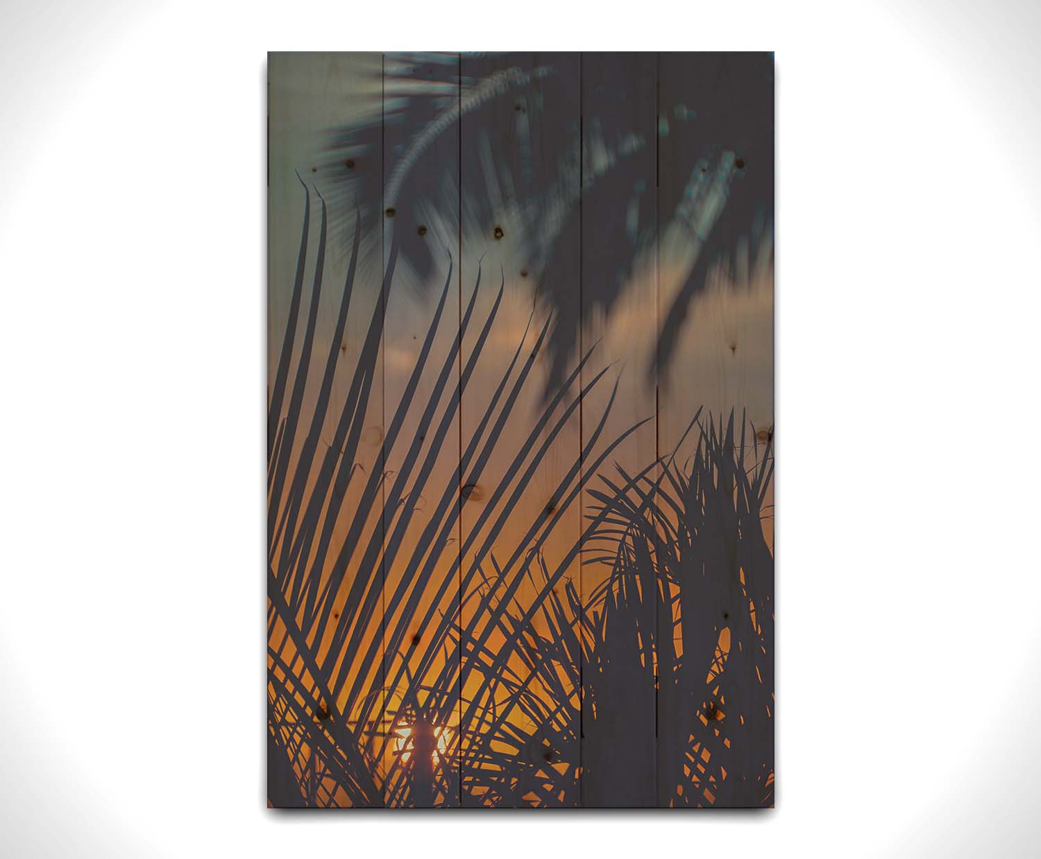 A photo of silhouetted palms at sunset. Printed on a wood pallet.