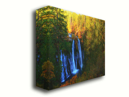 A photograph of Burney Falls in California. Taken from above and away from the falls, the photo gives a full view of the water pouring down the cliff face. The surrounding forest is beginning to turn orange for autumn. Printed on canvas.