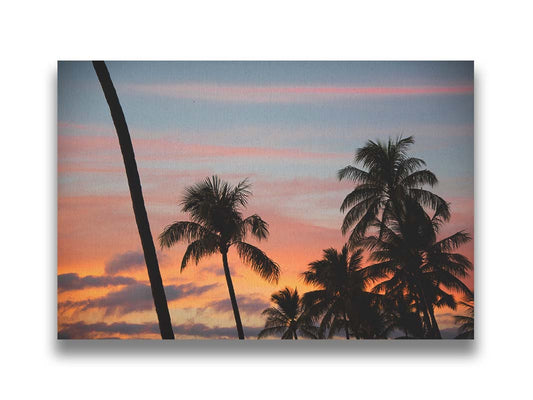 A photograph of Hawaiʻian palm trees, sihouetted against a sunset sky in orange, pink, and blue. Printed on canvas.