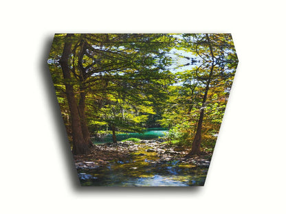 A photograph of the Guadalupe River in Gruene, Texas. Trees and foliage thrive around the water source, creating a lush green scene. The river reflects a vibrant turquoise behind the trees. Printed on canvas.