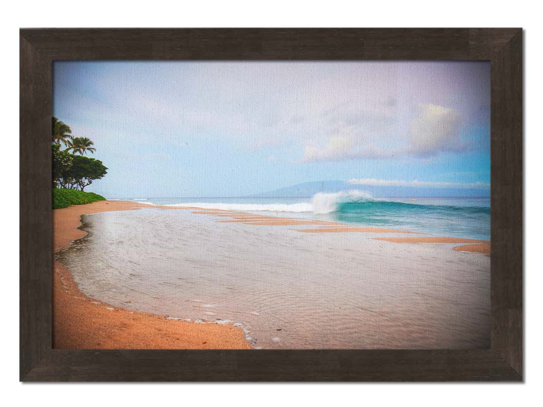 A refreshing photograph of Hawai'i's Ka'anapali beach, with cool blue waves rolling onto shore and mountains in the distance. Printed on canvas and framed.