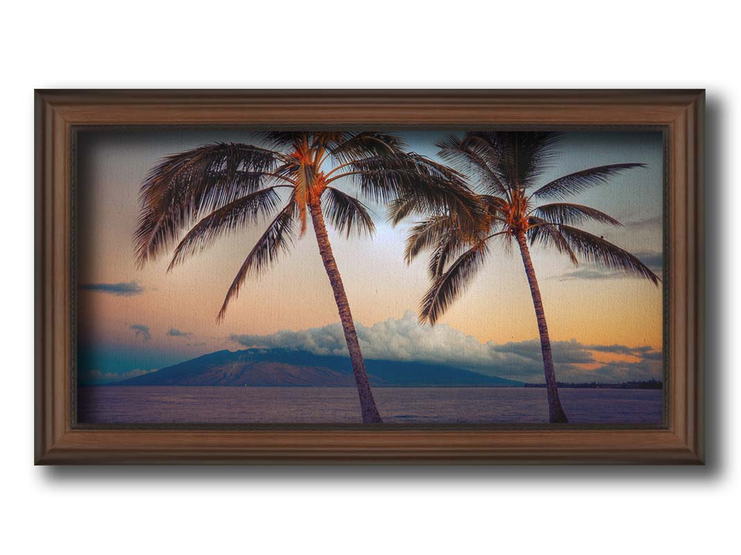 A photo of two palm trees in Maui at sunset, with the sea and cloud-topped mountains in the background. Printed on canvas and framed.