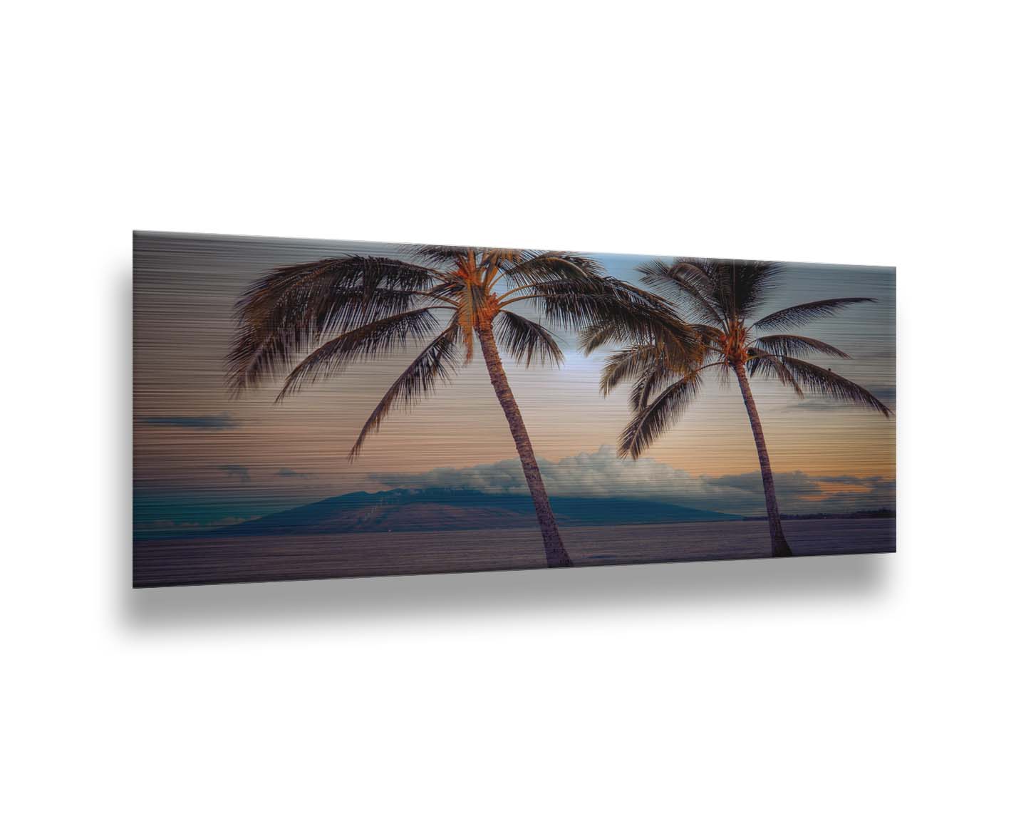 A photo of two palm trees in Maui at sunset, with the sea and cloud-topped mountains in the background. Printed on metal.