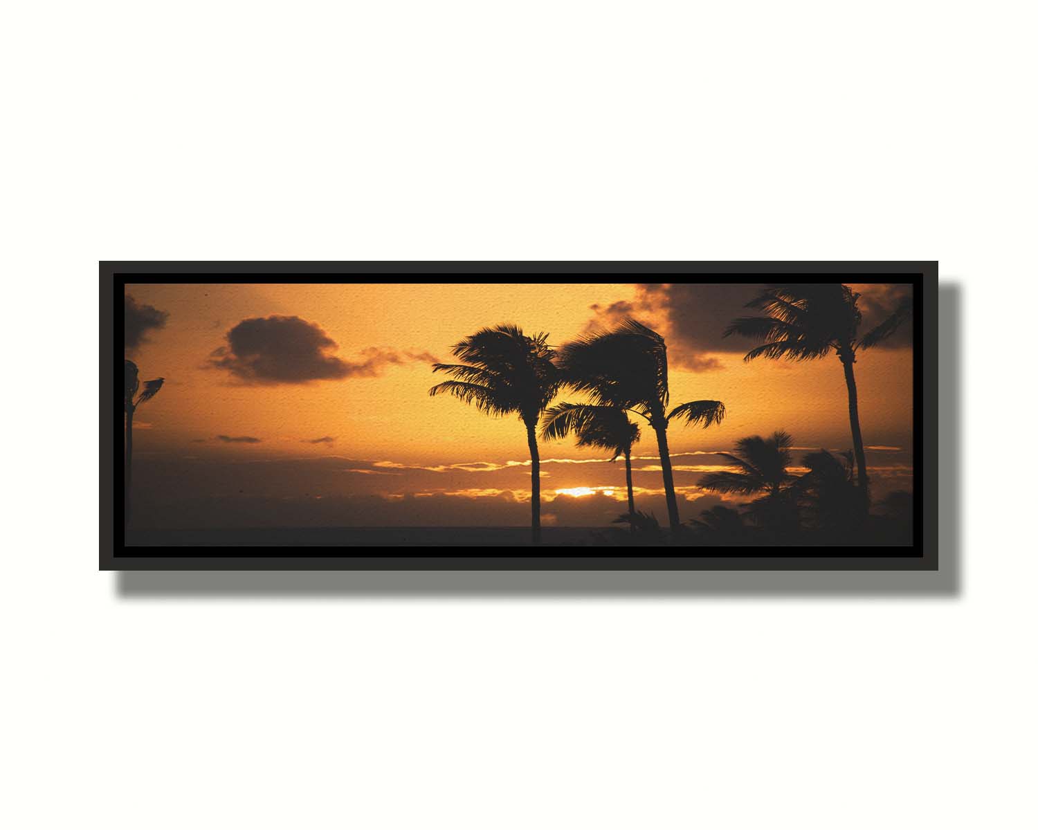 A photograph of an orange sunset over the sea, with striking palm trees silhouetted against the sky in Maui, Hawaiʻi. Printed on canvas in a float frame.