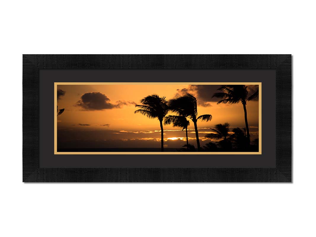 A photograph of an orange sunset over the sea, with striking palm trees silhouetted against the sky in Maui, Hawaiʻi. Printed on paper, matted, and framed.