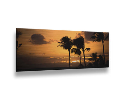 A photograph of an orange sunset over the sea, with striking palm trees silhouetted against the sky in Maui, Hawaiʻi. Printed on metal.