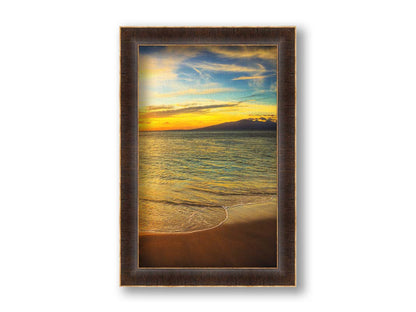 A photograph of a colorful sunset with a majestic mountain on the horizon, looking out over the sea on the coast of Maui, Hawaiʻi. Printed on canvas and framed.