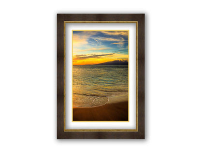 A photograph of a colorful sunset with a majestic mountain on the horizon, looking out over the sea on the coast of Maui, Hawaiʻi. Printed on paper, matted, and framed.