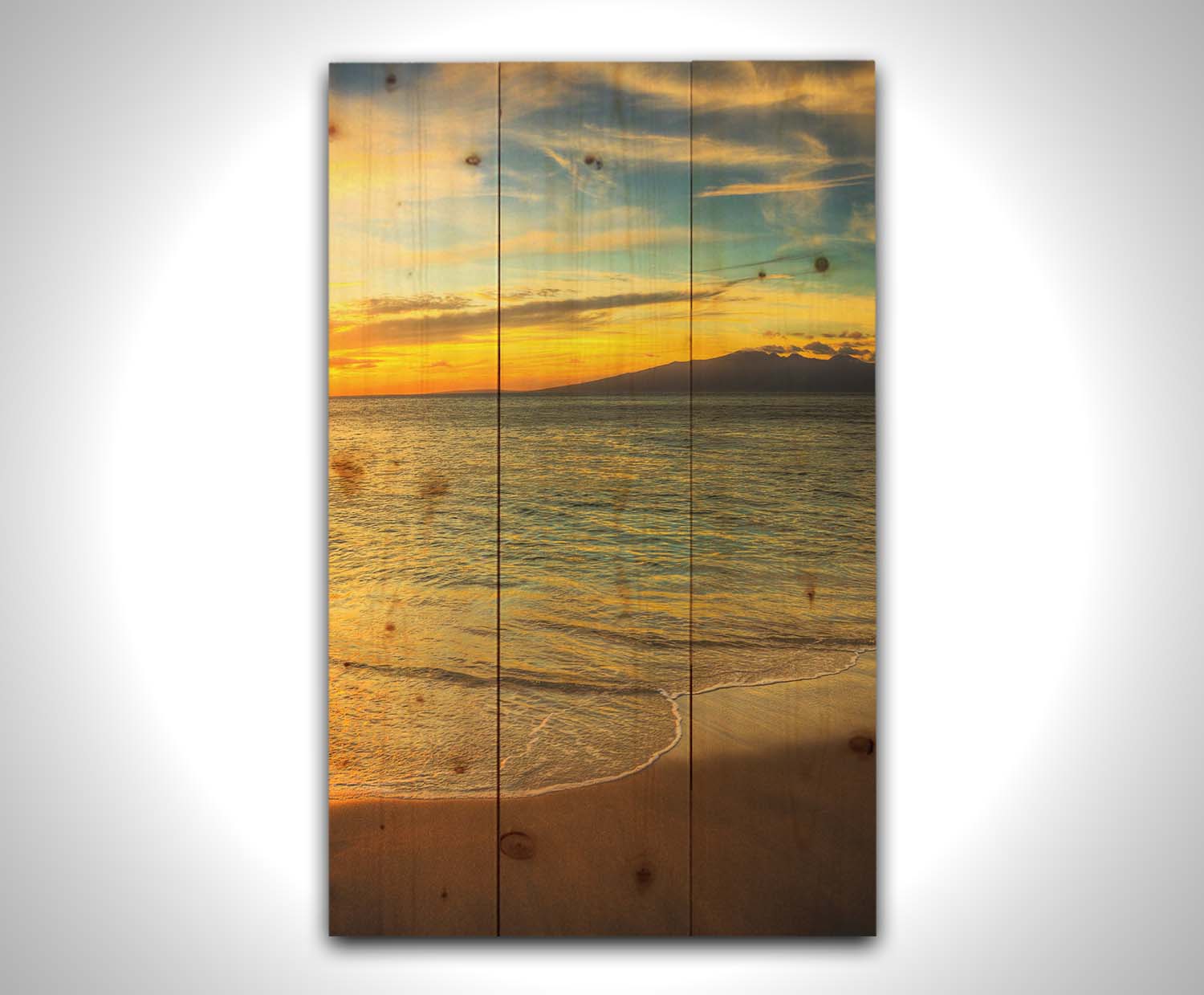 A photograph of a colorful sunset with a majestic mountain on the horizon, looking out over the sea on the coast of Maui, Hawaiʻi. Printed on a wood pallet.