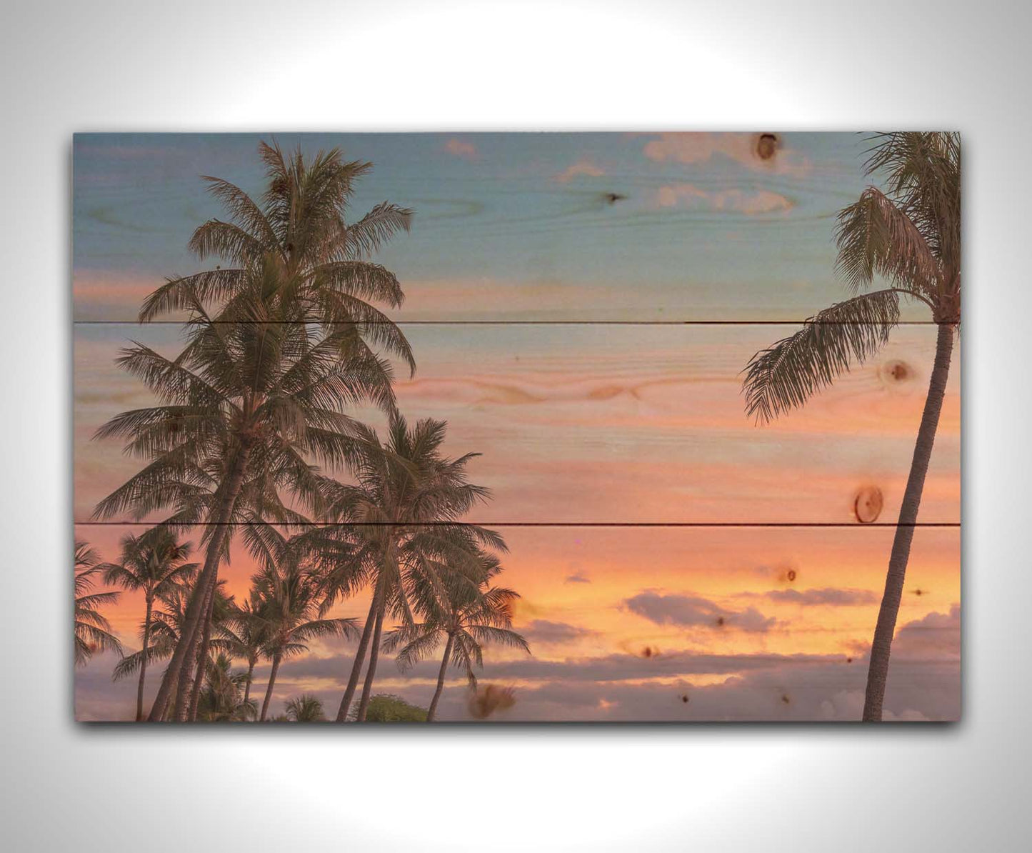 A photograph of Hawaiʻian palm trees, backed by a sunset sky in orange, pink, and blue. Printed on a wood pallet.