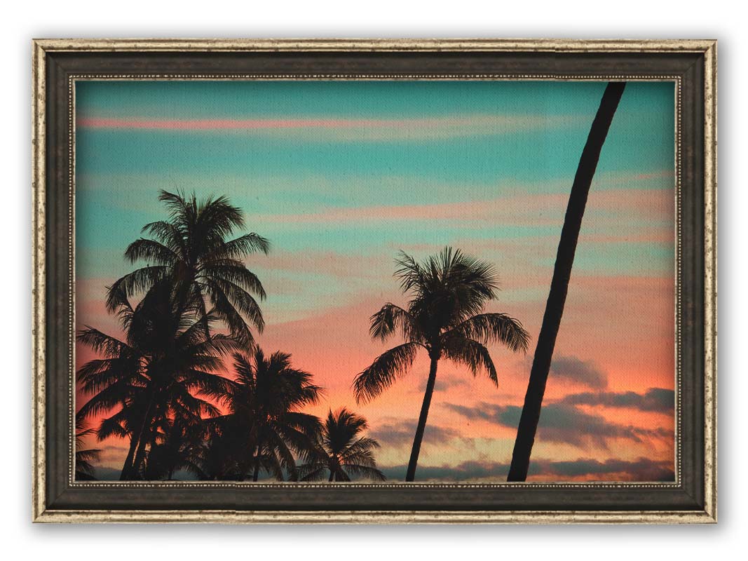 A photograph of Hawaiʻian palm trees, sihouetted against a sunset sky in orange, pink, and blue. Printed on canvas and framed.