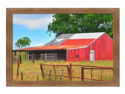 A photograph of a red barn, with a Texas flag painted on the roof. It is surrounded by red ranch fences and grassy fields. Printed on canvas and framed.