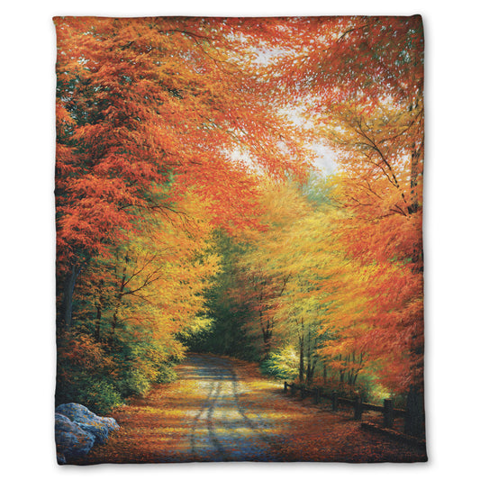 Coral fleece throw blanket with a painted autumn forest design. Red, orange, and yellow trees line a road winding through the forest.