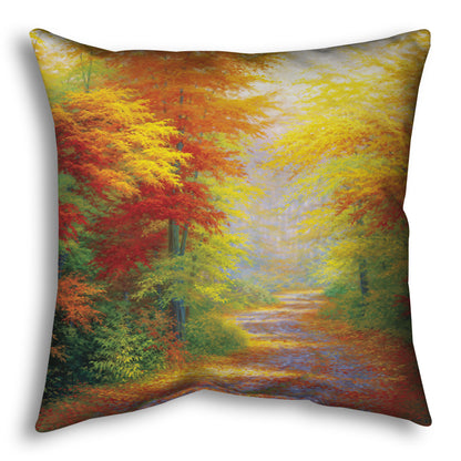 A throw pillow designed with a painting of a road winding through a forest during fall. The green, yellow, red, and orange foliage and trees shed leaves that line the path.