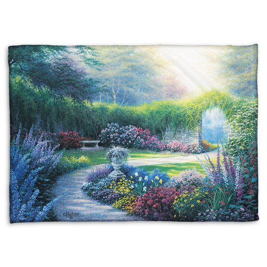 A coral fleece blanket designed with a painting of a serene path through a garden filled with bushes of flowers bathed in a gentle light.