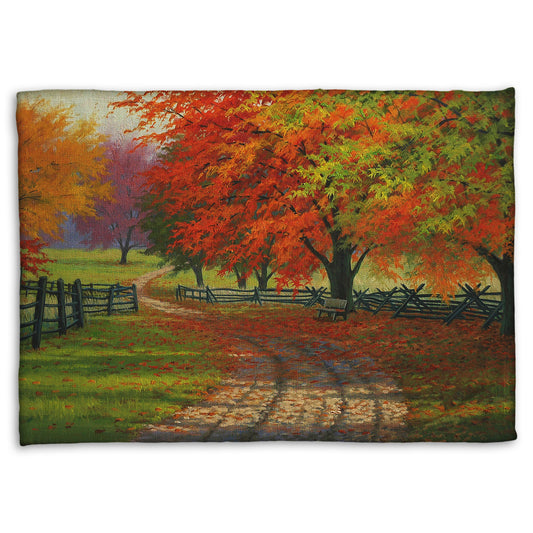 A fleece throw blanket designed with a painting of a road winding through a fenced field, surrounded by multicolored fall maple trees.