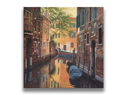 A painting of a canal alleyway between old brick buildings in Venice, Italy, during the day. The buildings reflect off the water in which a few small wood boats float. Printed on canvas.