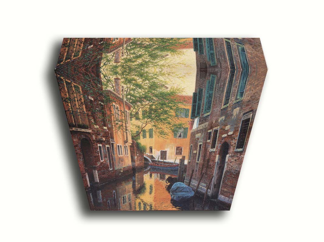 A painting of a canal alleyway between old brick buildings in Venice, Italy, during the day. The buildings reflect off the water in which a few small wood boats float. Printed on canvas.