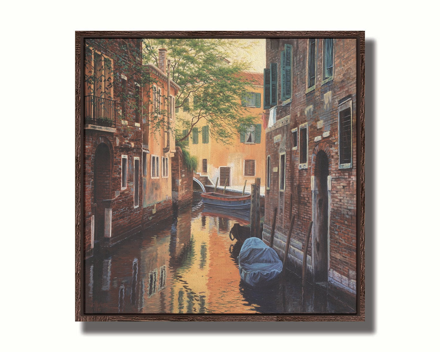 A painting of a canal alleyway between old brick buildings in Venice, Italy, during the day. The buildings reflect off the water in which a few small wood boats float. Printed on canvas in a float frame.