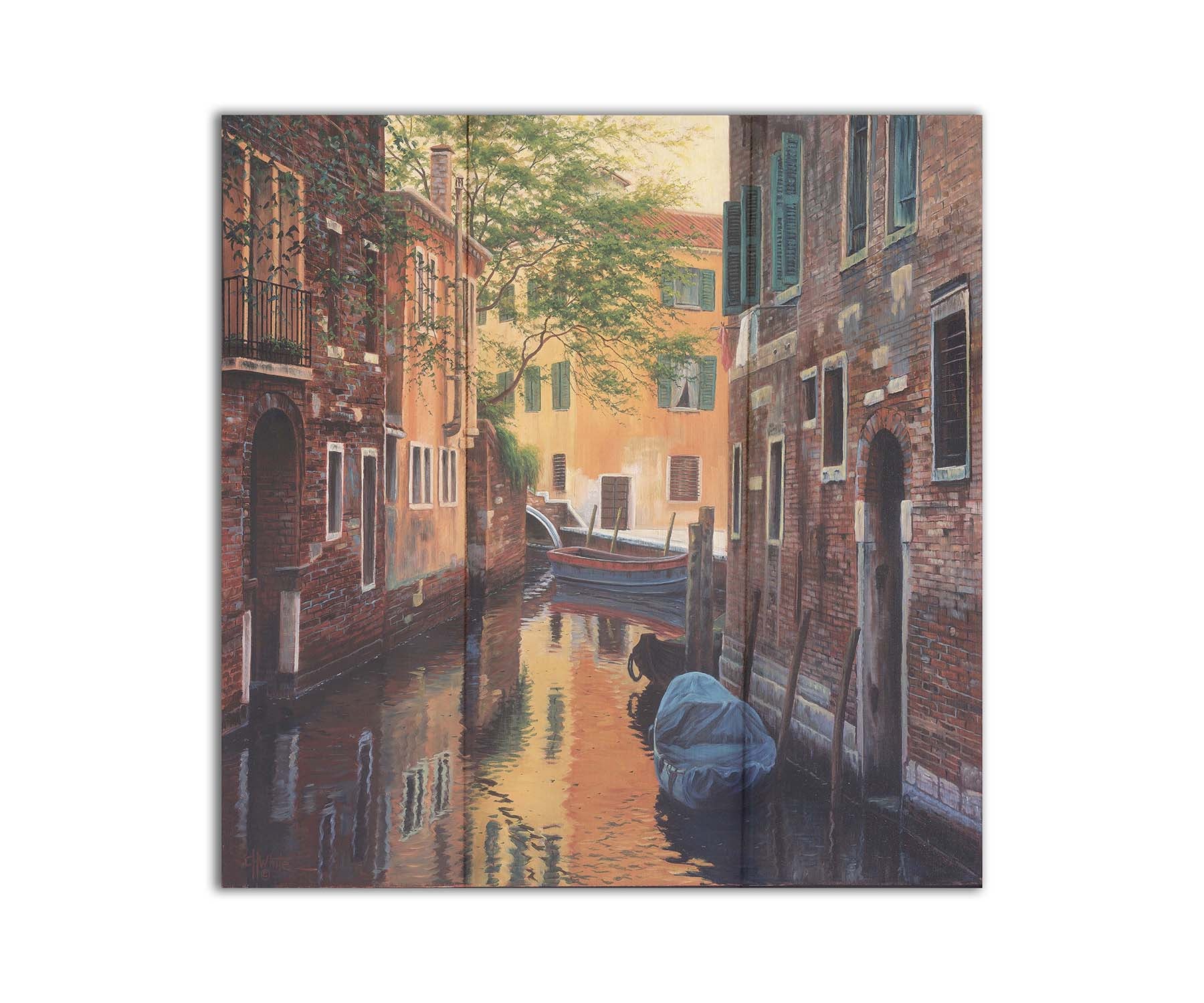 A painting of a canal alleyway between old brick buildings in Venice, Italy, during the day. The buildings reflect off the water in which a few small wood boats float. Printed on a box board.