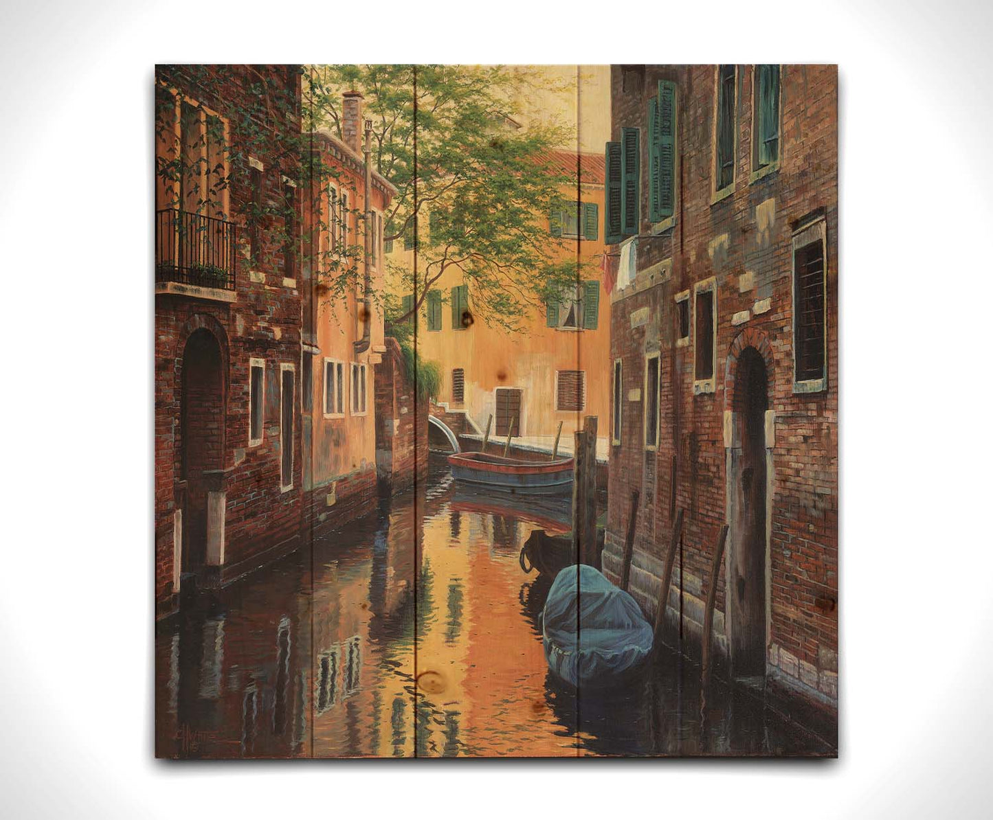 A painting of a canal alleyway between old brick buildings in Venice, Italy, during the day. The buildings reflect off the water in which a few small wood boats float. Printed on a wood pallet.