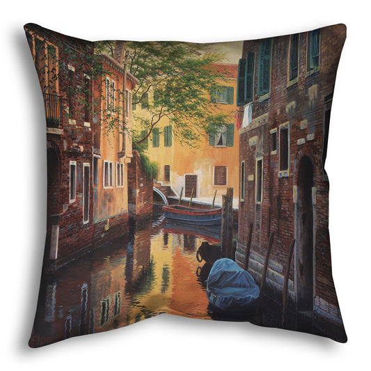A throw pillow designed with a painting of a canal alleyway between old brick buildings in Venice, Italy, during the day. The buildings reflect off the water in which a few small wood boats float.