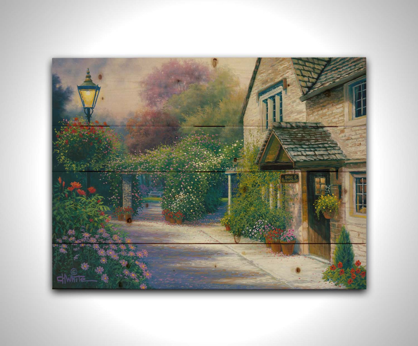 A painting of a bed and breakfast storefront, with a streetlamp-lined path leading to the garden full of blooming flowers. Printed on a wood pallet.