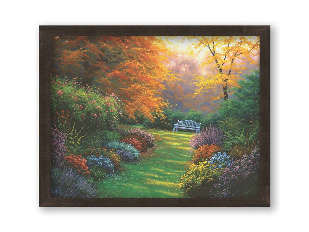 A painting of a garden path during fall. The trees surrounding the garden have turned orange and yellow. A grassy path through the garden is surrounded by bushes of flowers in every color, and a bench can be seen up ahead. Printed on canvas and framed.