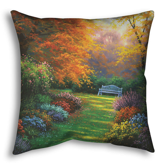 A throw pillow designed with a painting of a garden path during fall. The trees surrounding the garden have turned orange and yellow. A grassy path through the garden is surrounded by bushes of flowers in every color, and a bench can be seen up ahead.